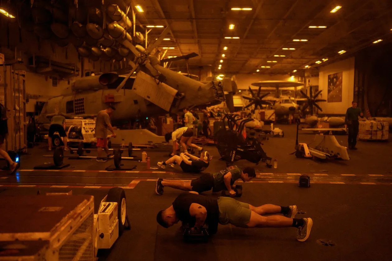 Amerikai haditengerészek a USS George Washington fedélzetén futballmeccset néznek // A második képen pedig a legénység tagjai gyúrnak a hajó repülőhangárjában – Fotó: Ed Ou / Reuters