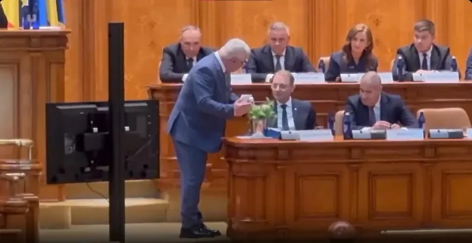 Ninel Peia, a PACE – Románia az első parlamenti csoport szenátora épp odaadja ajándékait Luca Niculescu kijelölt miniszterelnöknek – Képernyőmentés a parlamenti ülés élő közvetítéséből