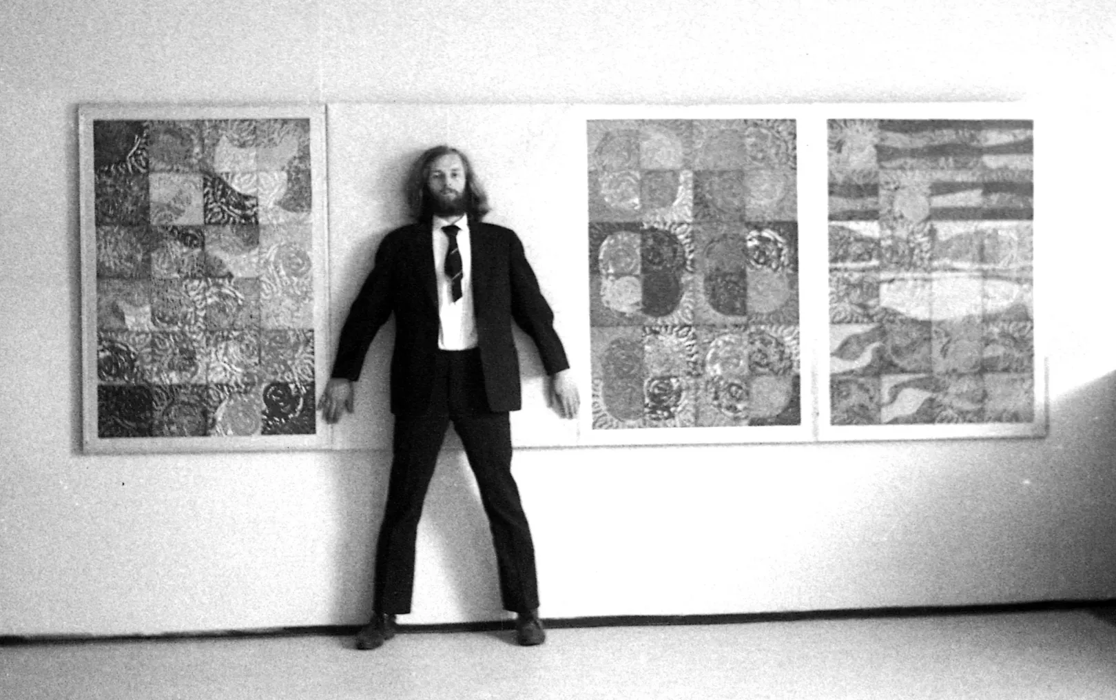 Galántai György képzőművész 1973-ban, a Becsomagolt kiállítás című akciójához készült fotón. Miután a hivatalos művészeti lektorátus a kiállításra szánt alkotásainak mintegy kétharmadát nem engedélyezte bemutatni, Galántai az elutasított műveket becsomagolva állította ki. A képen a Négy évszak sorozat betiltott Nyár című alkotása előtt áll. A fotóból készült meghívót műkritikusoknak és a kulturális élet vezetőinek küldte el – Forrás: Artpool